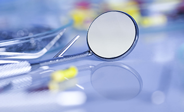 A magnifying glass resting on a surface with various medical supplies in the background.
